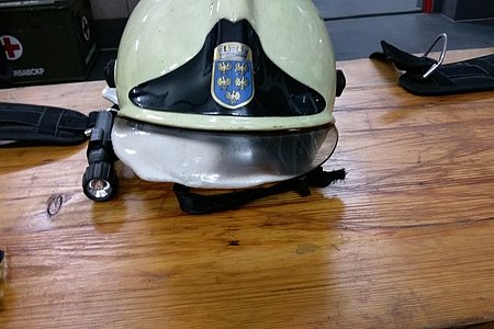 Helm mit angeschmolzenem Visier aufgrund der Hitzebelastung im Container